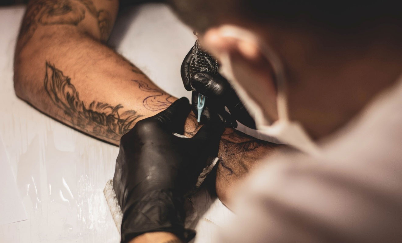 tattoo artist working on a hand tattoo
