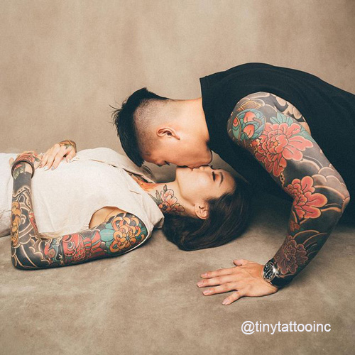kissing couple with matching full sleeve tattoos